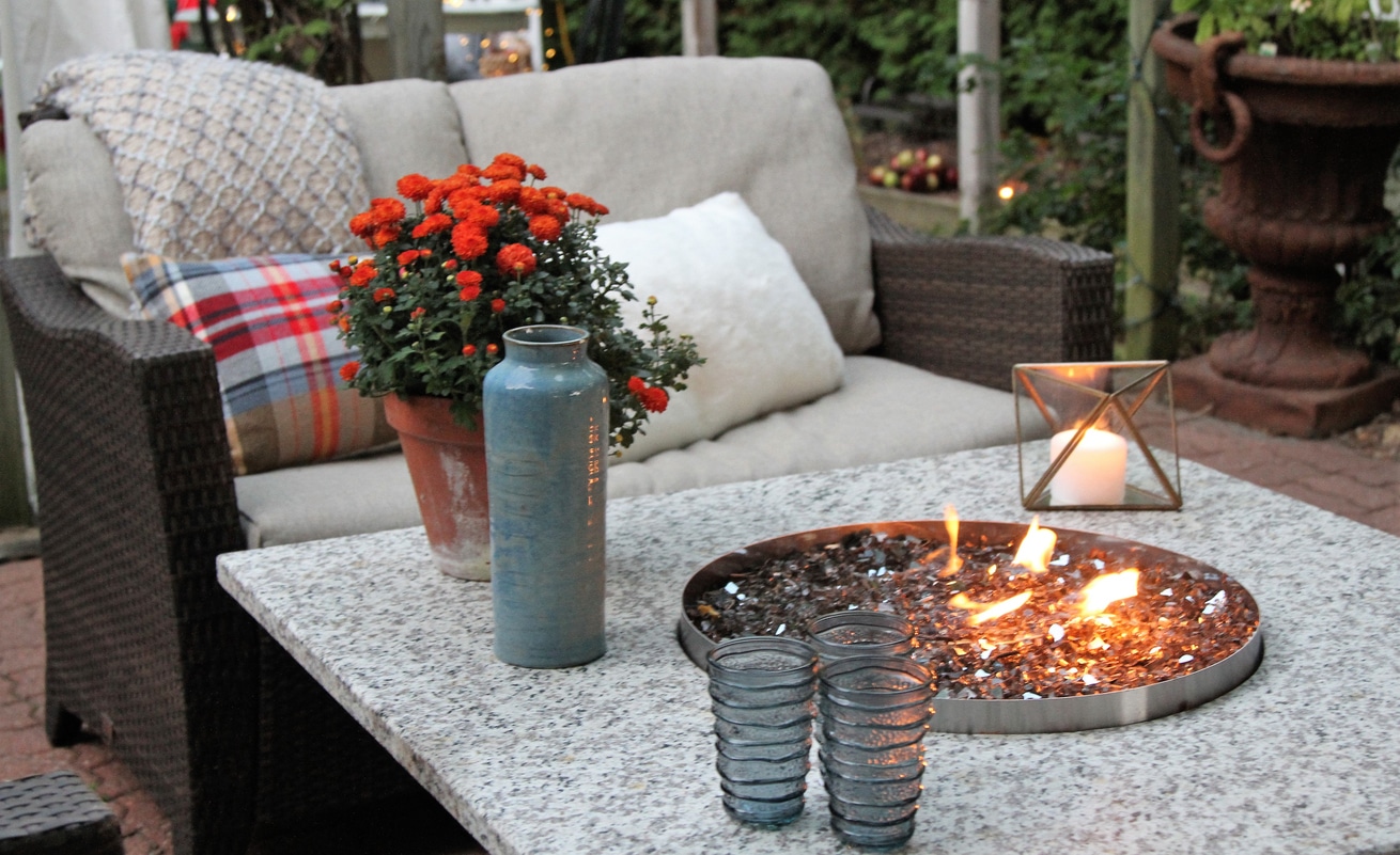 fire pit in the middle of a table with cosy autumn seating arrangement with plaid pillows